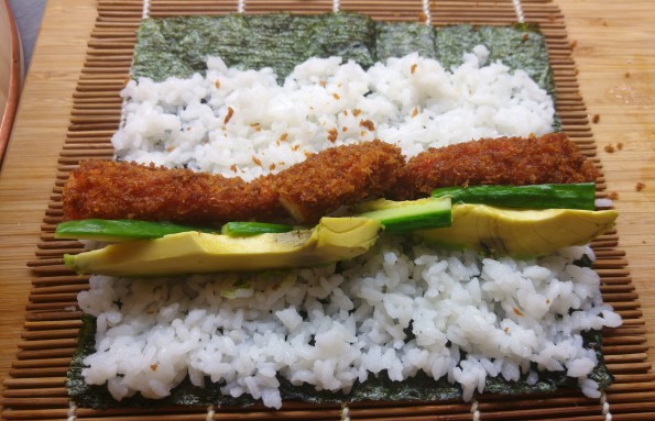 Sushirolle belegen mit frittierter Garnele, Avocado und Gurke